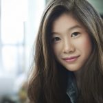 Indoor image of beautiful happy Asian girl looking at camera. Day time indoor image of beautiful, happy late teen girl or young woman with long brown hair of Asian ethnicity looking at camera. Hade and shoulders, horizontal image with copy space and selective focus.